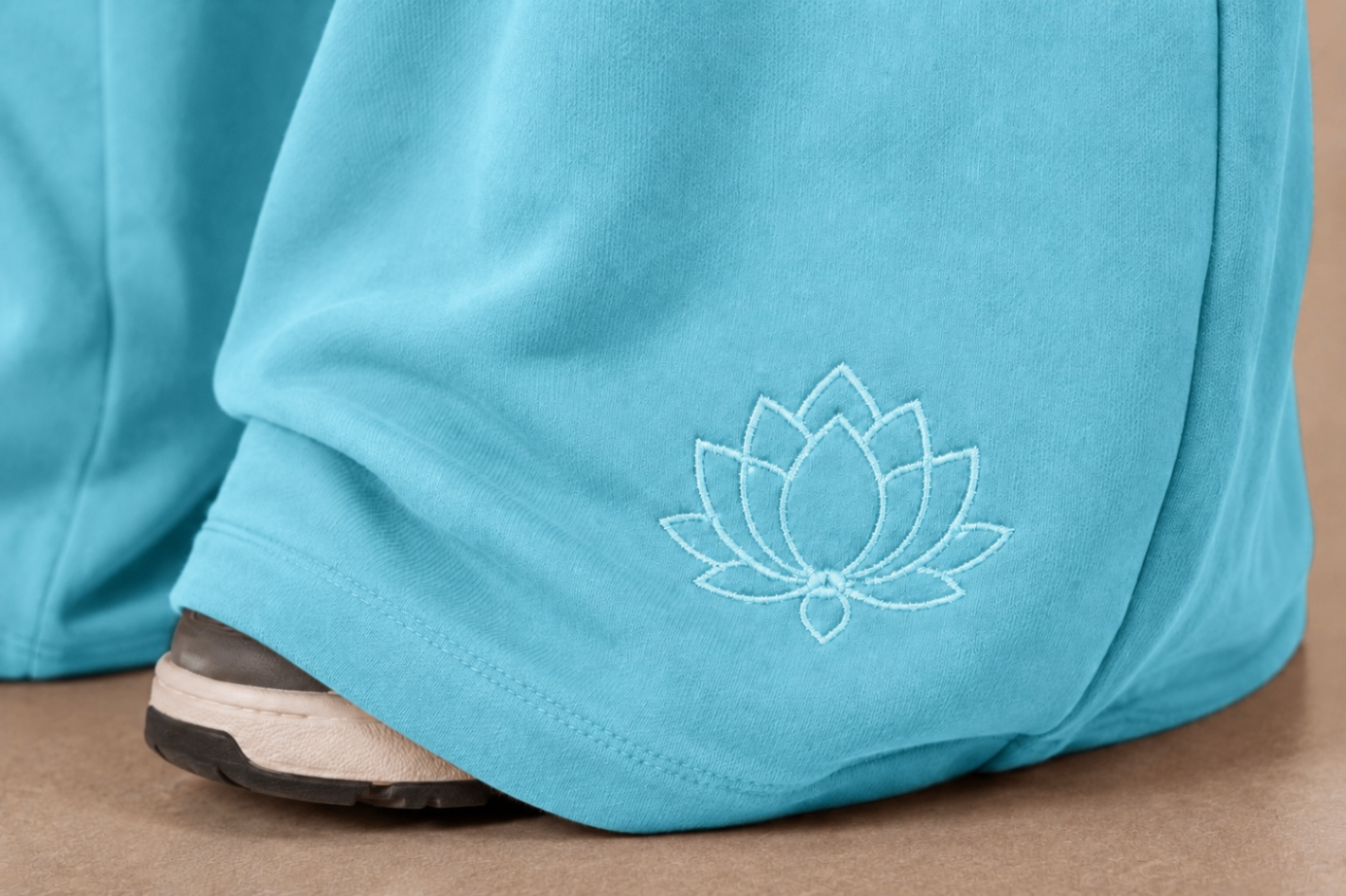 Close-up of the lotus embroidery on the hem of the Lotus Blue tracksuit bottoms.