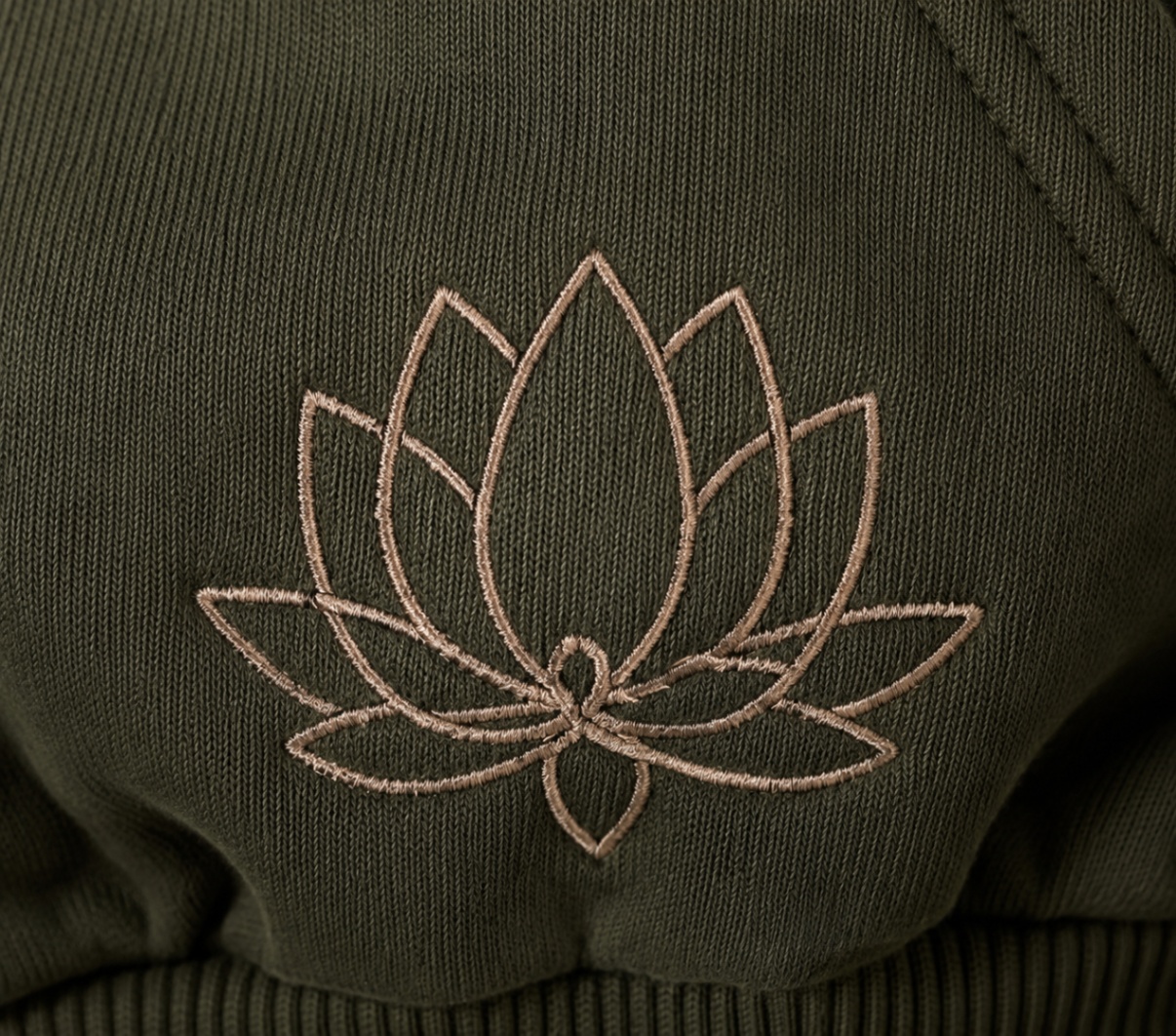 Detail of the embroidered lotus emblem on the Lotus Original Green cropped zip-up hoodie.
